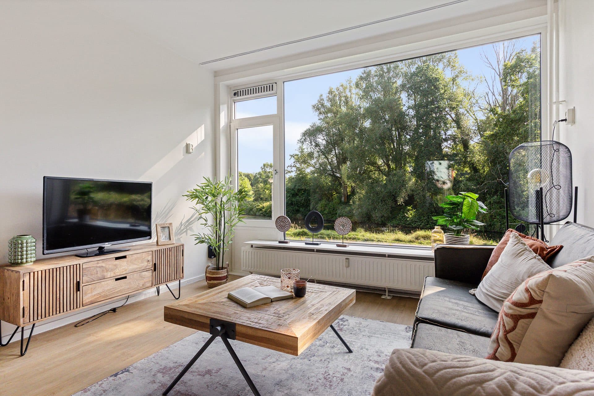 Lichte gestylede woonkamer met grote raampartij en uitzicht op groen, verkoopklaar gemaakt in Noord-Nederland