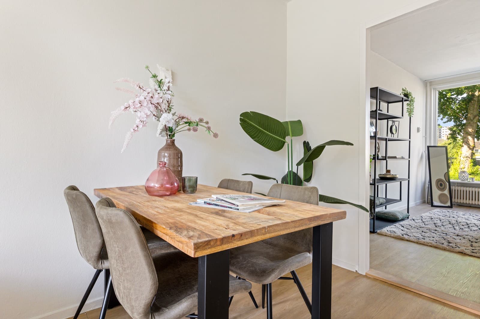 Gestylede eethoek met een houten eettafel, zachte stoelen en verse bloesem op tafel, klaar voor de bezichtiging